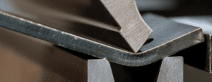 Processo de corte e dobra de aço em chapa metálica industrial realizado com dobradeira CNC de alta capacidade na Mikro Stamp, empresa de estamparia em Campinas.
